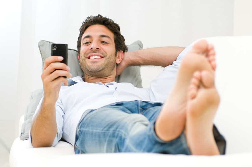 Man relaxing on sofa surfing his mobile smart phone