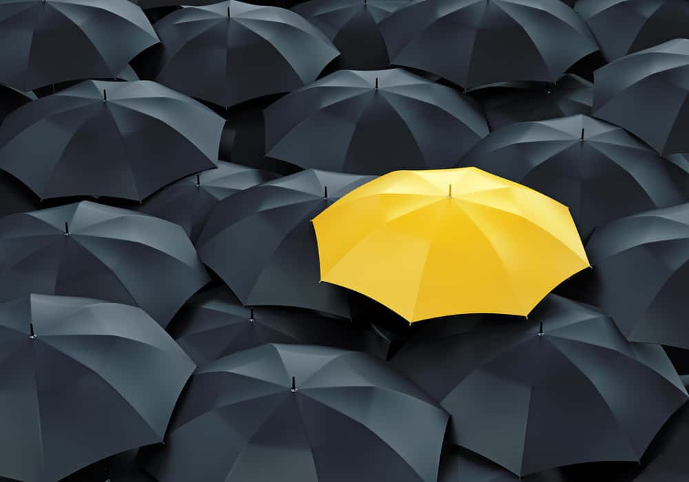 Uniuqe yellow umbrella in sea of black umbrellas