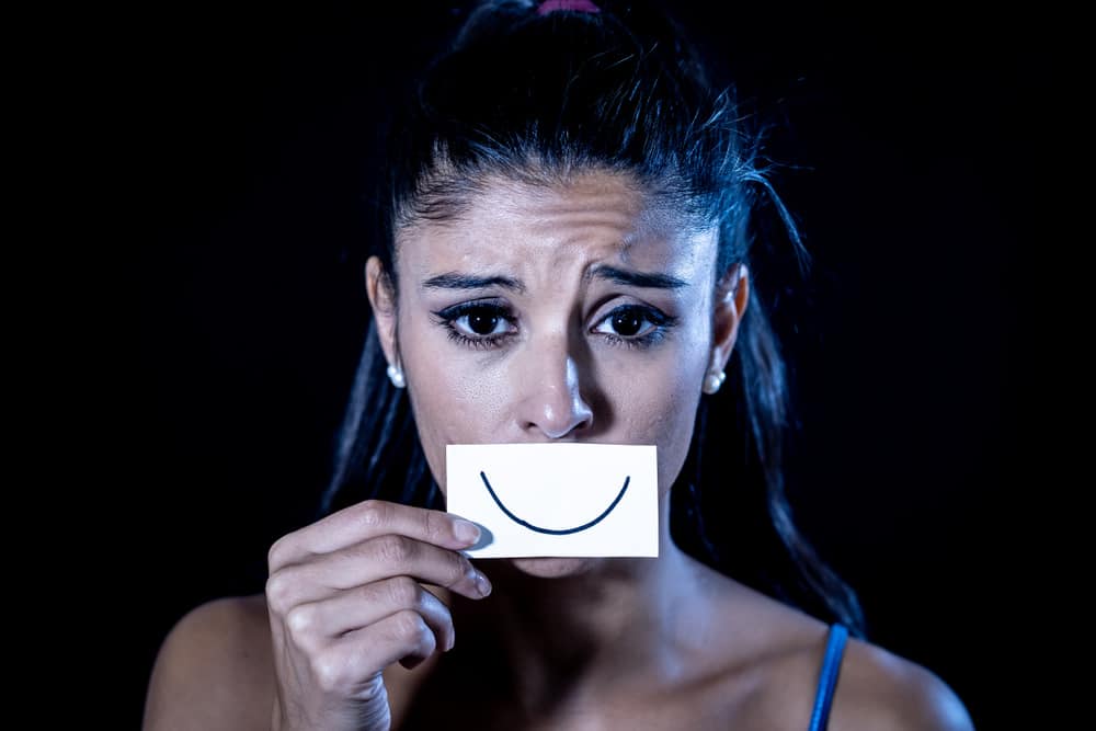 Sad woman with fake smile