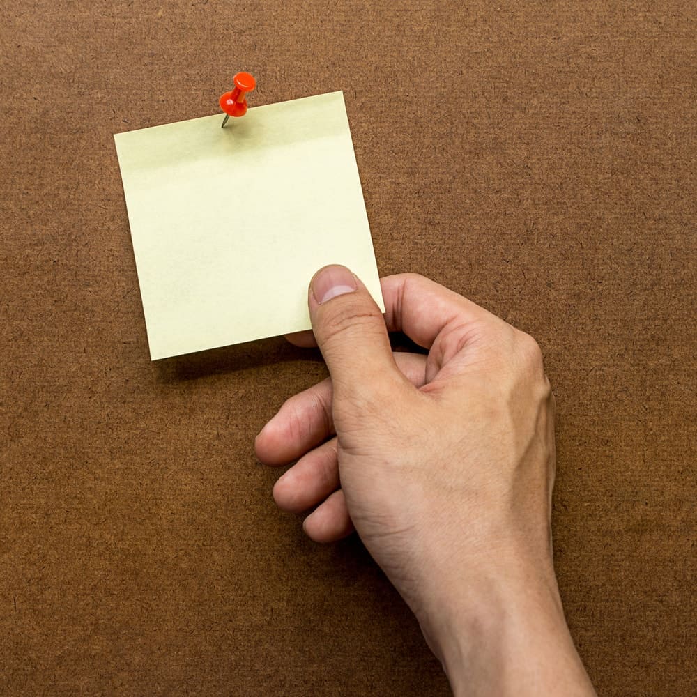 A hand holding a pinned yellow paper.