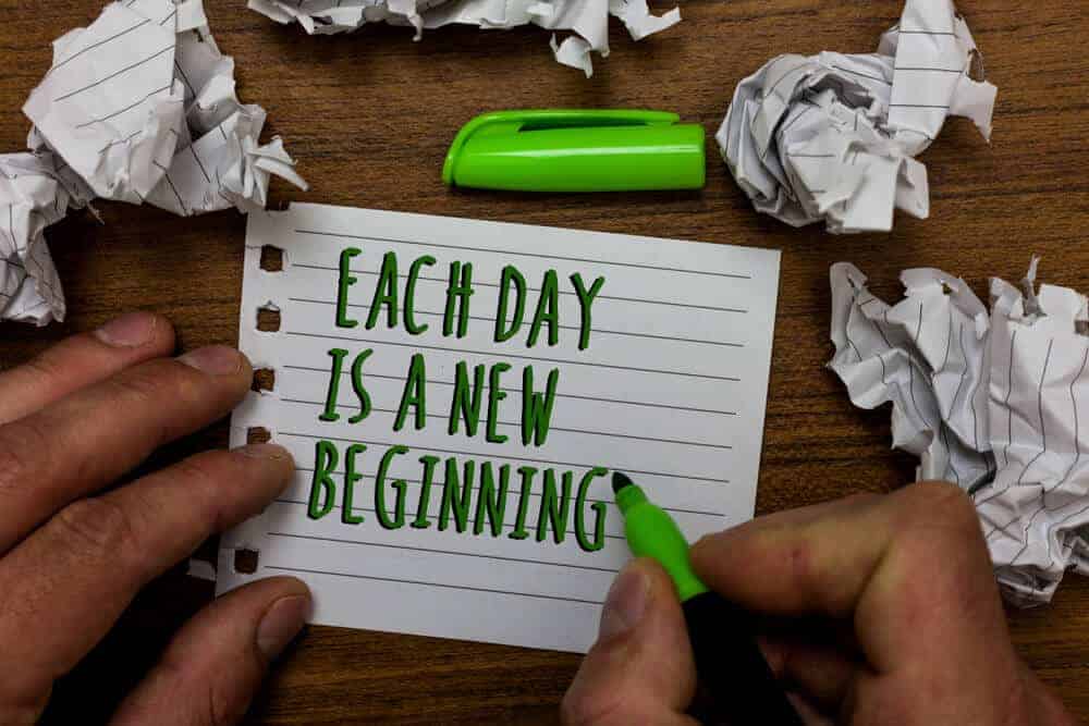 The quote "Each day is a new beginning" written on a piece of paper using a green marker.