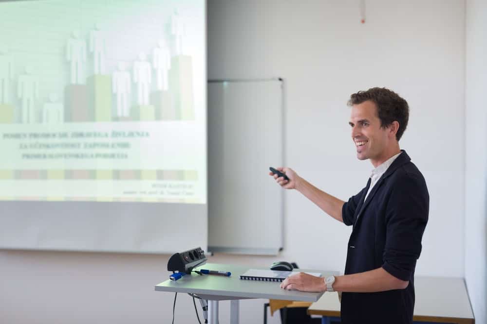 A man with a powerpoint clicker points it on the projector screen as he presents during the meeting.